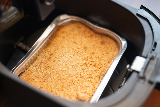 Fiskegrateng i en aliminiumsform, plassert i en airfryer skuff. bilde sett ovenfra